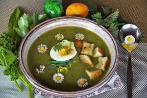 Green soup garnished with egg, croutons, and daisies.