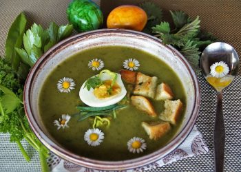 Green soup garnished with egg, croutons, and daisies.