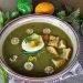 Green soup garnished with egg, croutons, and daisies.