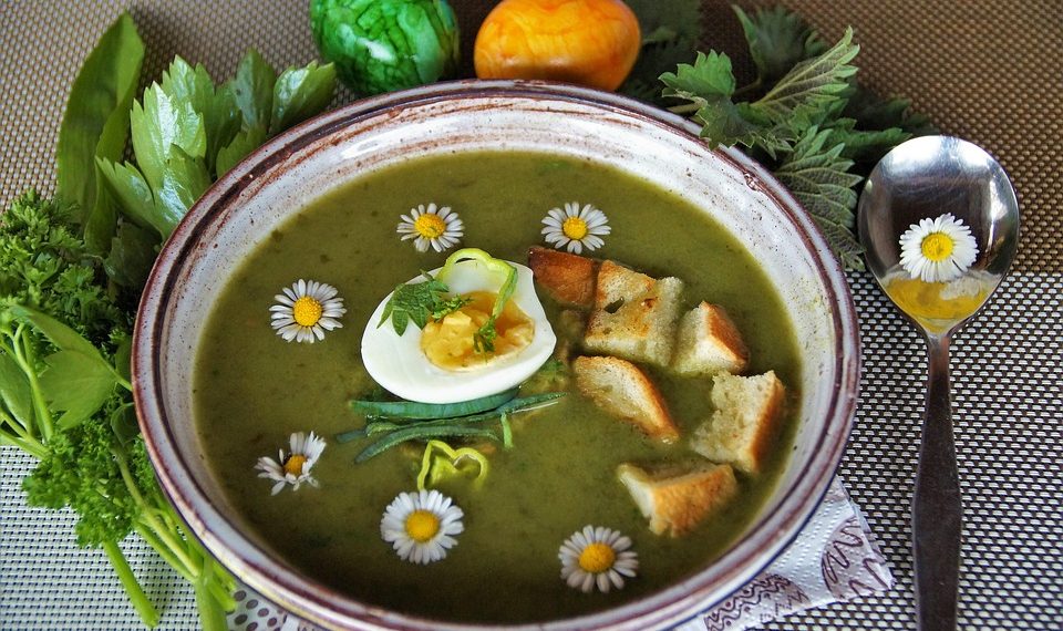 Green soup garnished with egg, croutons, and daisies.
