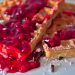 Waffles topped with vibrant berry sauce and powdered sugar.