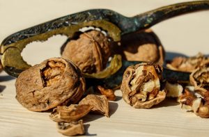 Cracked walnuts with nutcracker on wooden table.