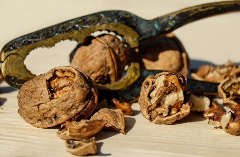 Cracked walnuts with nutcracker on wooden table.