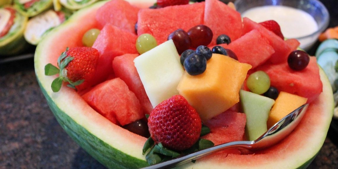 Fruit salad in watermelon bowl with diverse fresh fruits.
