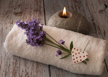 Lavender on towel beside candle for spa relaxation.