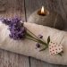 Lavender on towel beside candle for spa relaxation.