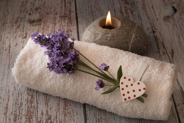 Lavender on towel beside candle for spa relaxation.