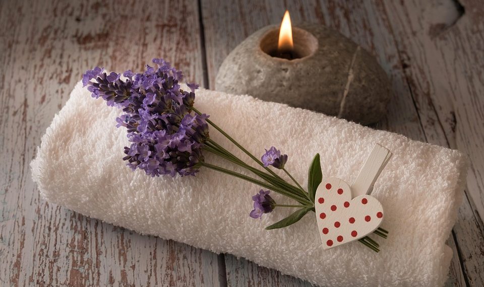 Lavender on towel beside candle for spa relaxation.