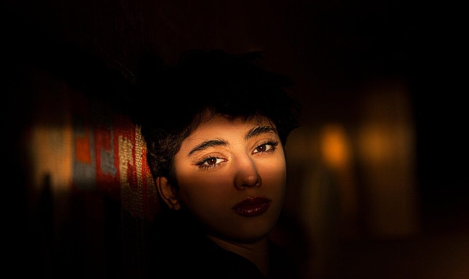 Shadowed face with intense gaze against a textured wall.
