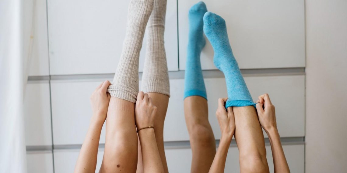 Two people pulling up blue and beige socks.