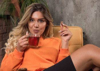 Woman enjoying tea and chocolate while relaxing on a chair.