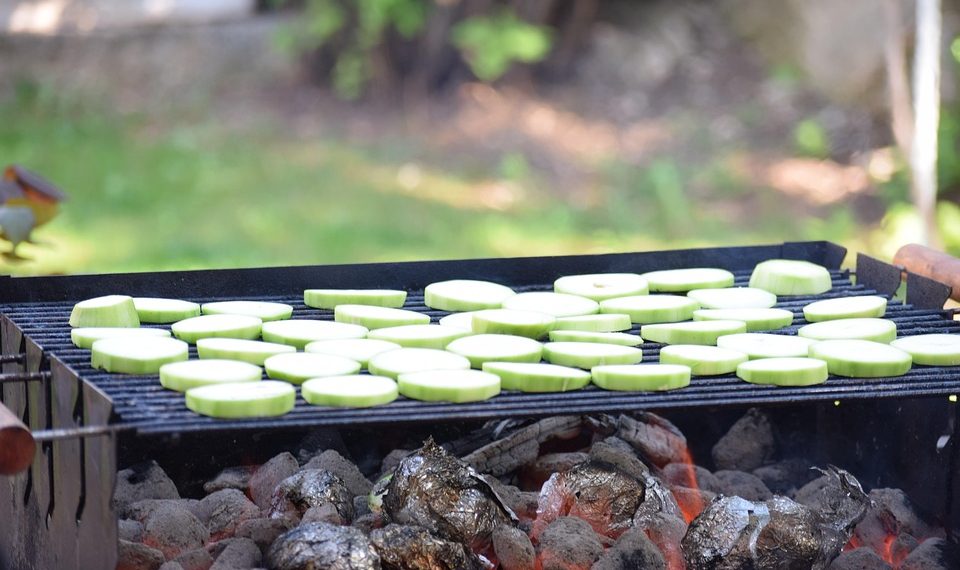 Grilling zucchini slices over hot coals.