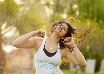 Woman joyfully dancing outdoors in a Zumba class.