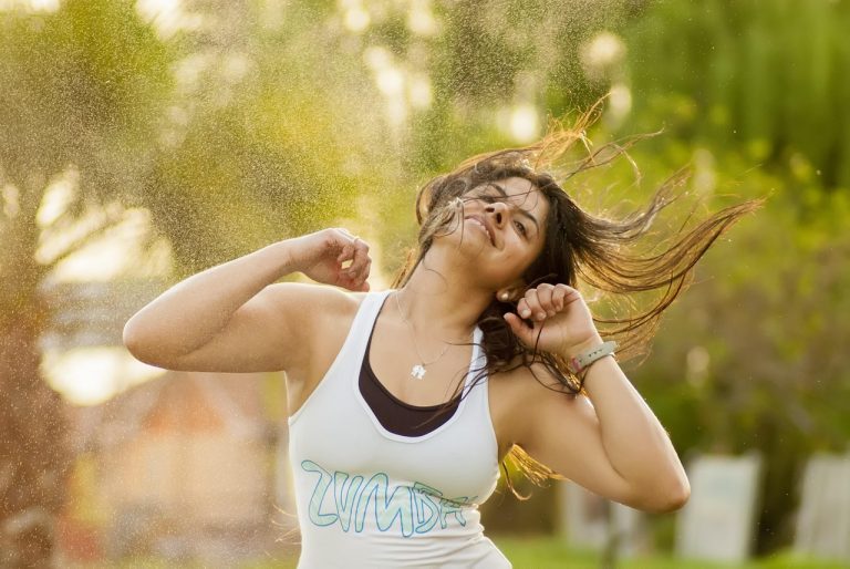 Woman joyfully dancing outdoors in a Zumba class.