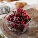 Beet salad with herbs in a glass bowl on wooden table.