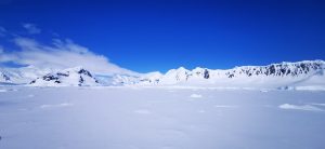 Snowy mountain range under a clear blue sky in Antarctica.
