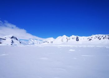 Snowy mountain range under a clear blue sky in Antarctica.