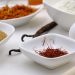 Saffron, sugar, flour, and egg arranged in white bowls for baking.