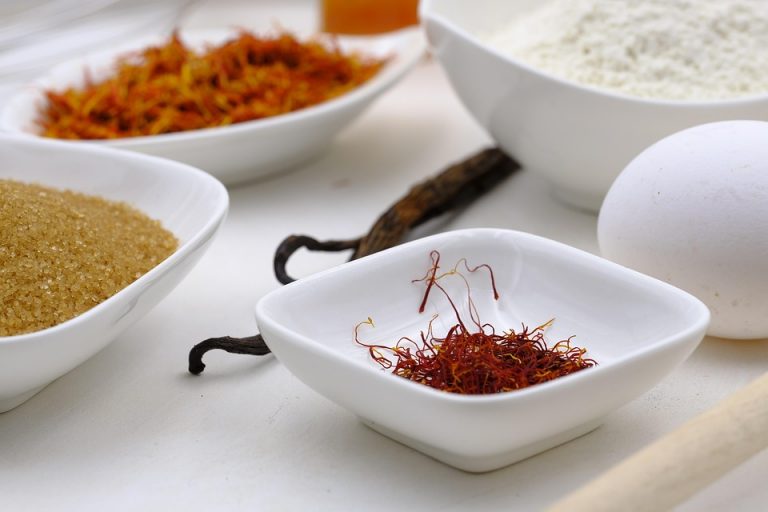 Saffron, sugar, flour, and egg arranged in white bowls for baking.