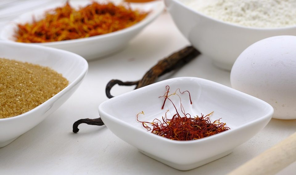 Saffron, sugar, flour, and egg arranged in white bowls for baking.