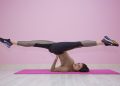 Woman performing yoga pose on pink mat in studio.