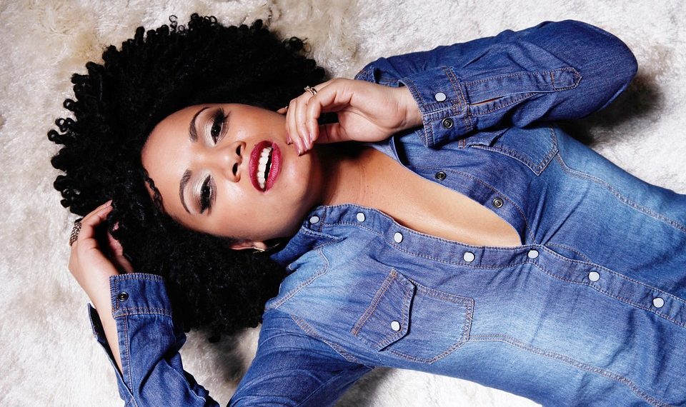 Woman in denim shirt lying on textured surface, relaxed expression.