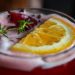 Refreshing hibiscus cocktail with orange slice garnish.