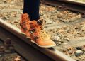 Walking on railway track in stylish orange sneakers.