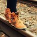 Walking on railway track in stylish orange sneakers.