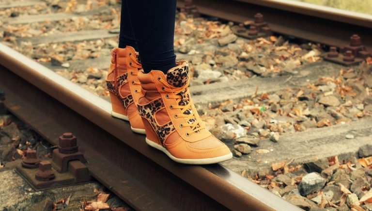 Walking on railway track in stylish orange sneakers.