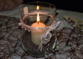 Elegant candle with ribbon decoration in glass holder.