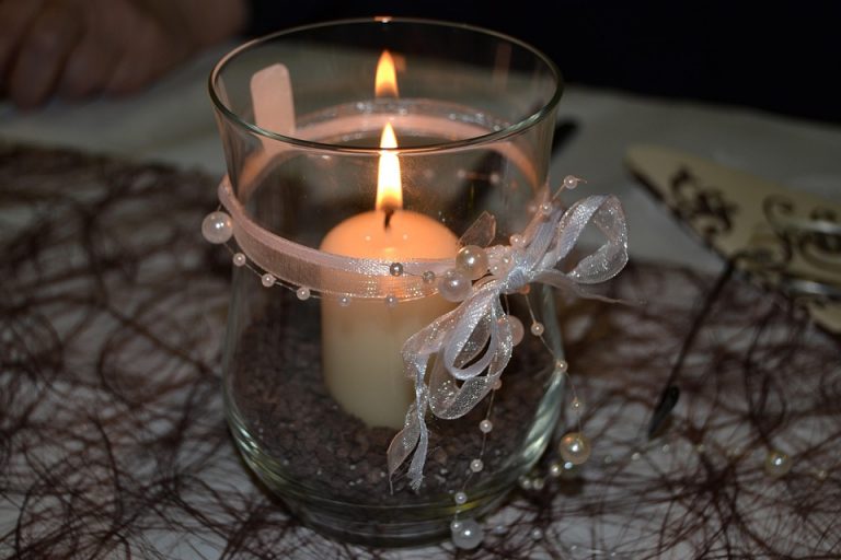 Elegant candle with ribbon decoration in glass holder.