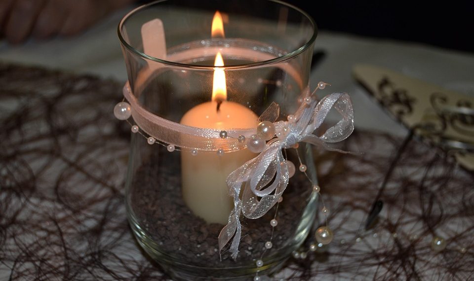 Elegant candle with ribbon decoration in glass holder.