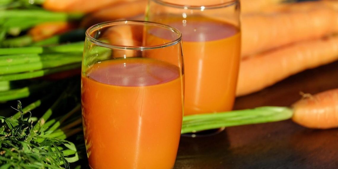 Carrot juice in glasses with fresh carrots.