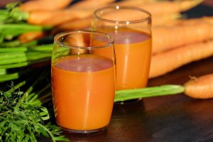 Carrot juice in glasses with fresh carrots.
