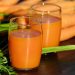 Carrot juice in glasses with fresh carrots.