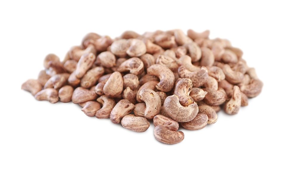 Raw cashew nuts piled on white background.