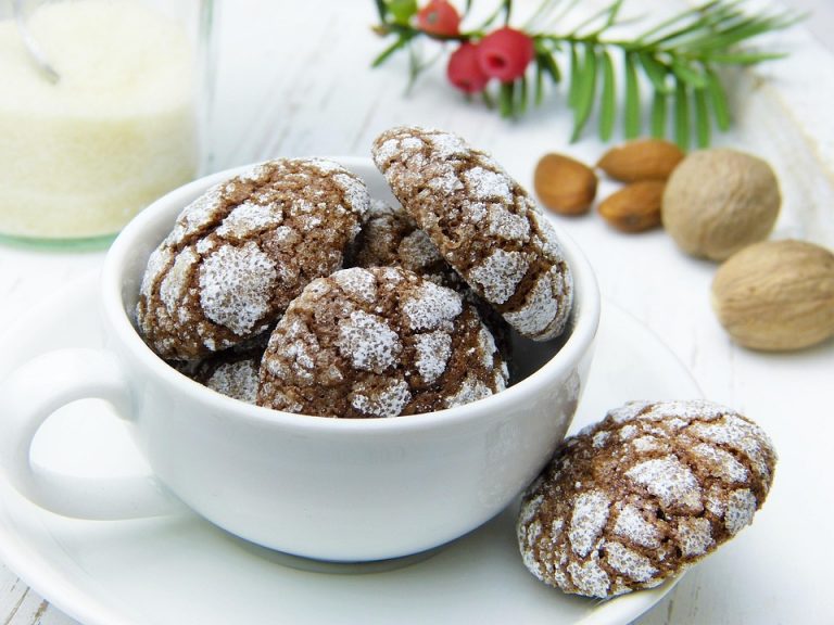 Chocolate crinkle cookies in a teacup with almonds nearby.