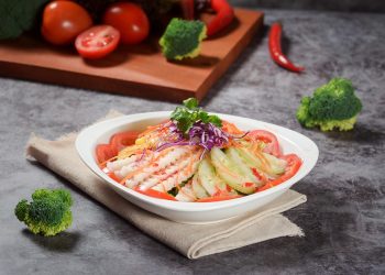 Fresh vegetable salad with tomatoes, cucumbers, and herbs, garnished with cilantro.
