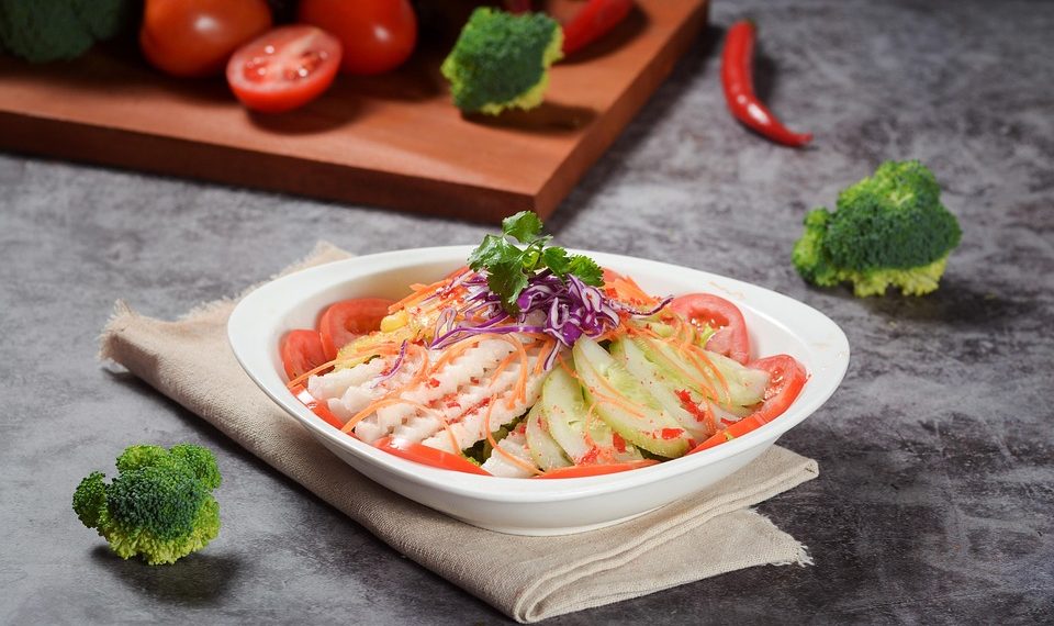 Fresh vegetable salad with tomatoes, cucumbers, and herbs, garnished with cilantro.