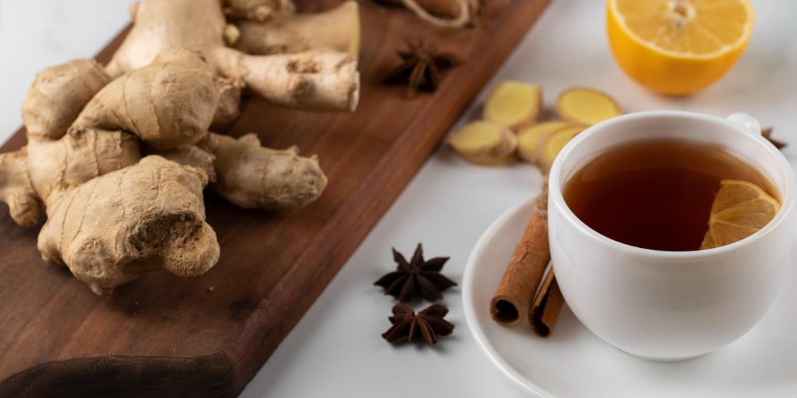 Ginger tea with lemon and cinnamon sticks on a table.