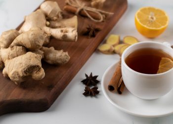 Ginger tea with lemon and cinnamon sticks on a table.