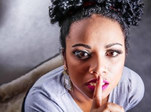 Woman gesturing silence with finger on lips.