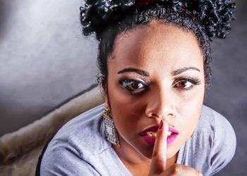 Woman gesturing silence with finger on lips.