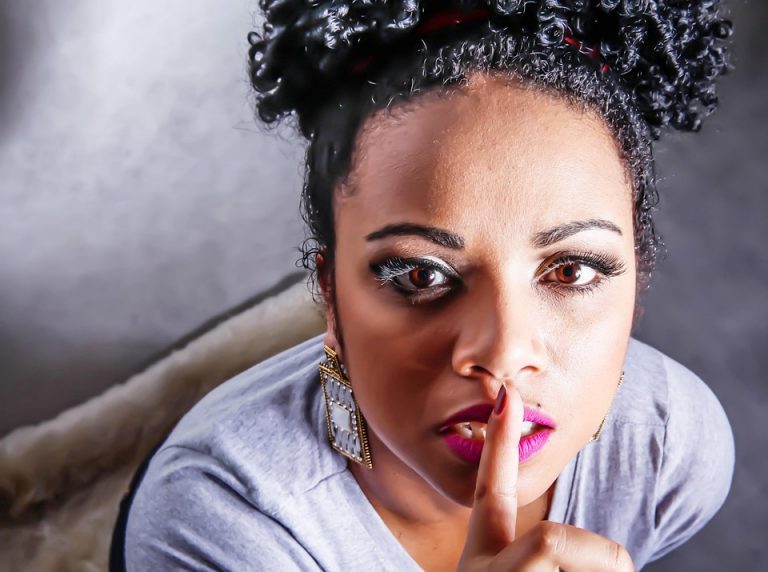 Woman gesturing silence with finger on lips.