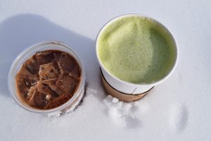 Chilled iced chocolate and hot matcha latte on snow.