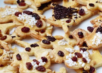 Cookies topped with raisins and chocolate sprinkles.