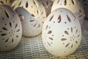 Decorative ceramic eggs with intricate cut-out patterns on display.