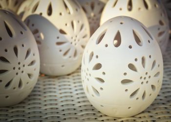 Decorative ceramic eggs with intricate cut-out patterns on display.