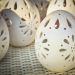 Decorative ceramic eggs with intricate cut-out patterns on display.